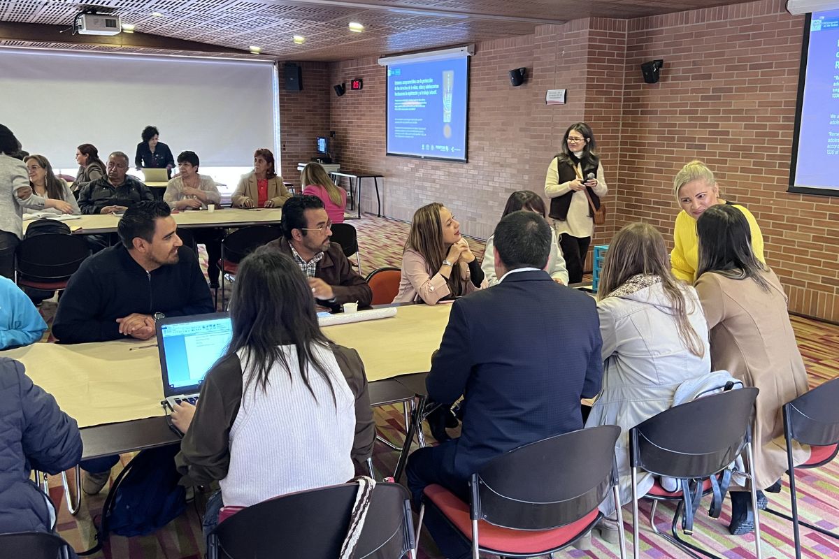 Foto de docentes reunidos en un salón de conferencias atentos a una persona que les está hablando