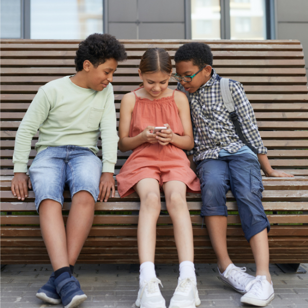 Dos niños viendo contenido en el celular que les muestra un niña