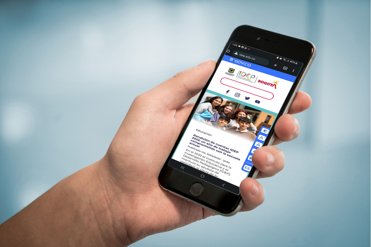 Imagen de una mano sosteniendo un celular en el cual se ve el portal web del IDEP