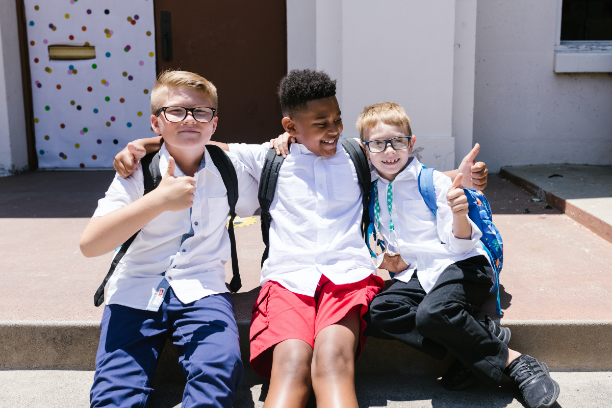 Tres niños sentados abrazados y sonrientes