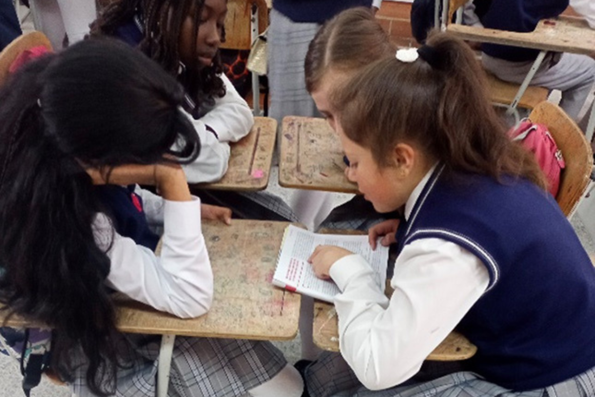 Foto de 4 niñas en su pupitre haciendo tareas