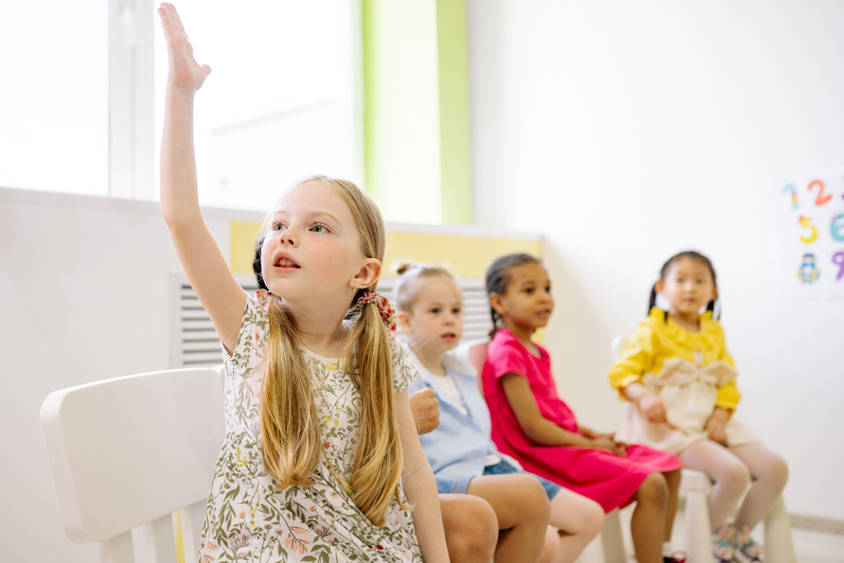 Foto de una niña levantando la mano para participar