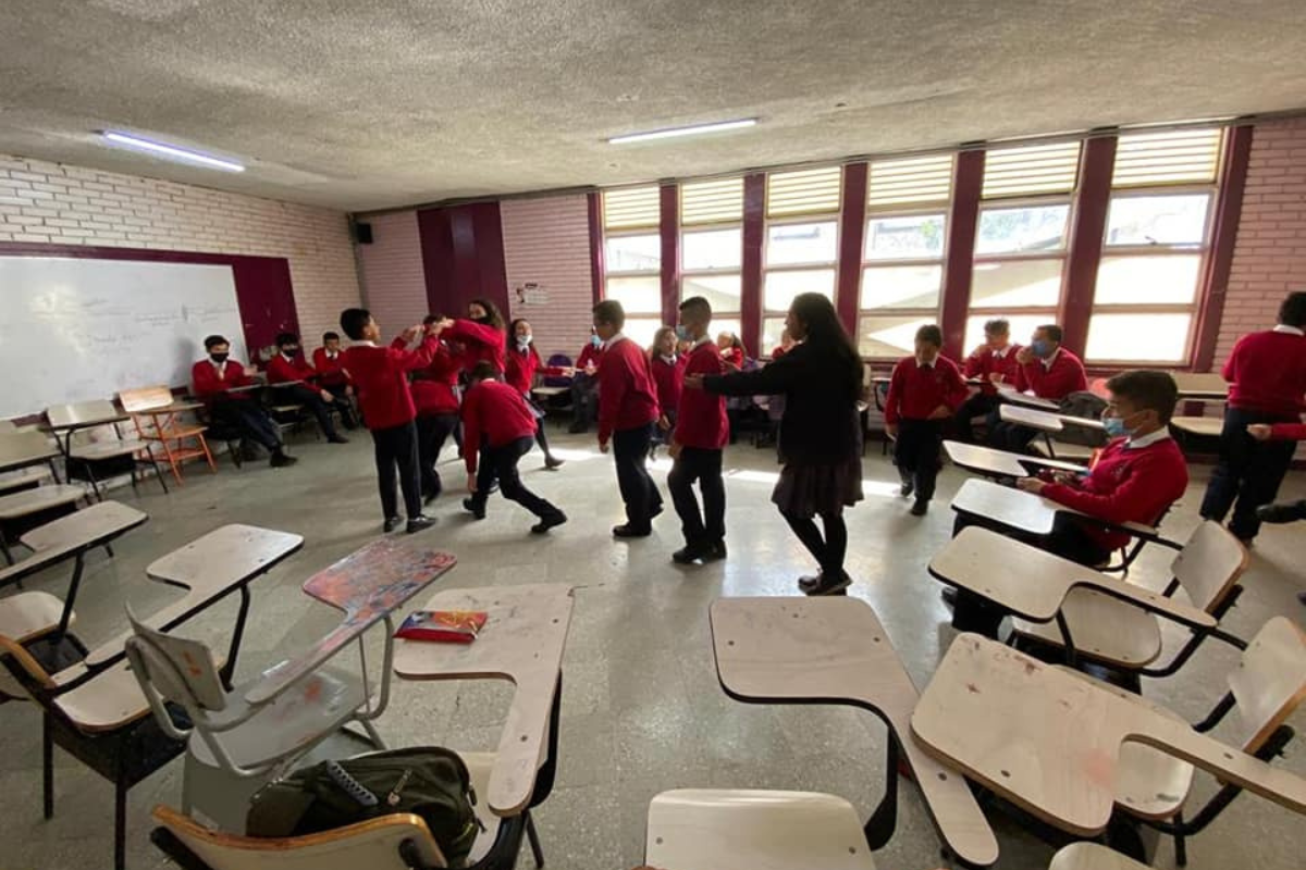 Imagen de un aula de clase con varios estudiantes y la foto del profesor José Antequera Guzmán