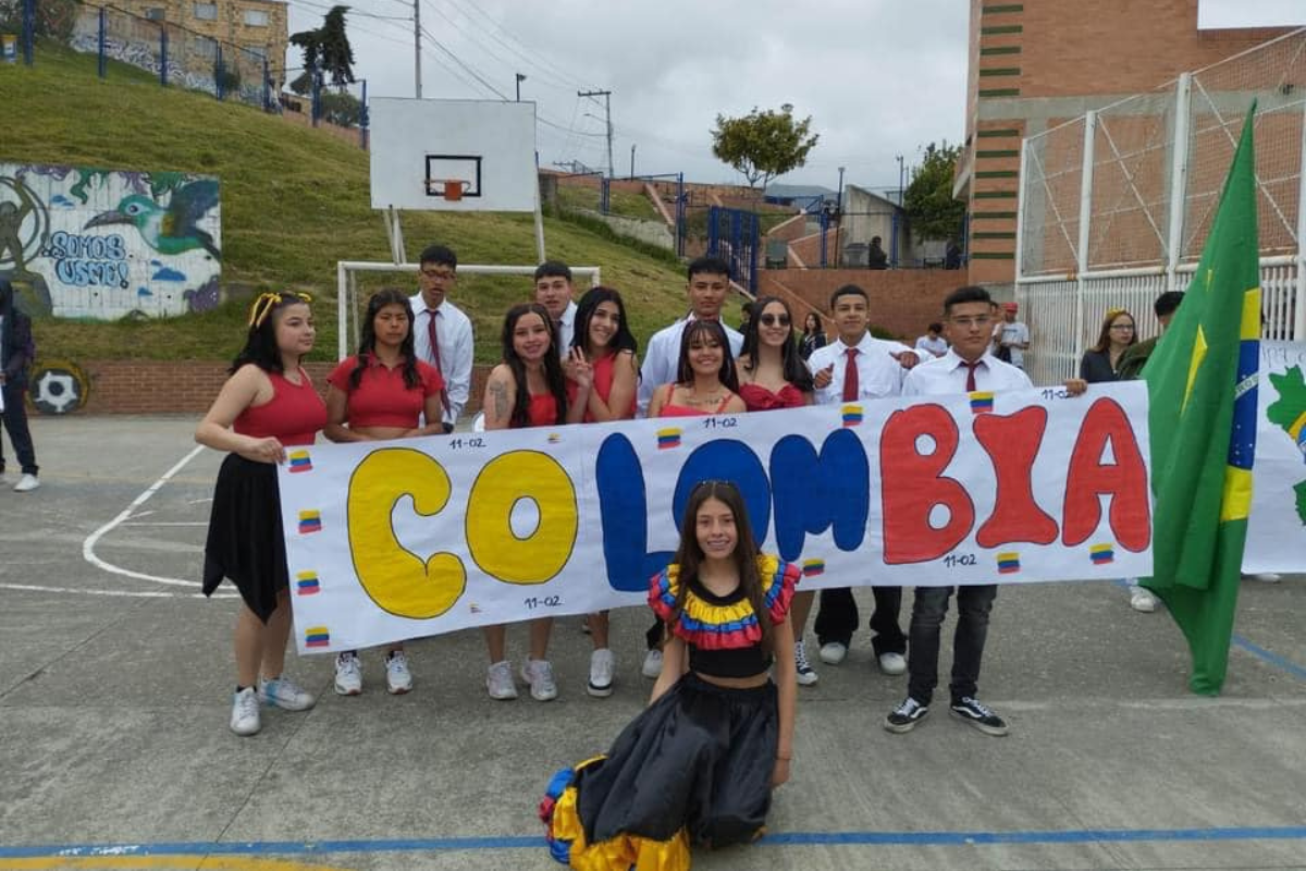 Estudiantes en el patio del colegio mostrando una pancarta que dice Colombia