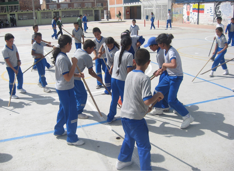 Estudiantes jugando con palos de escoba en el patio