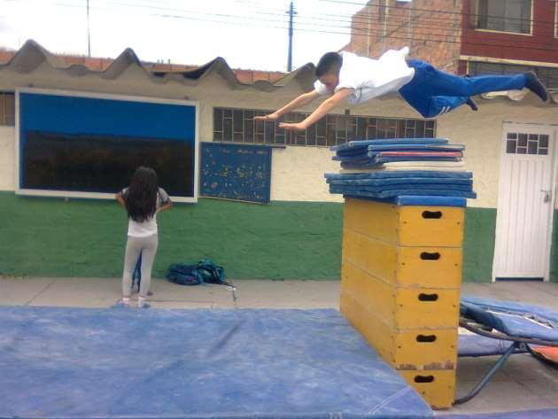 Un estudiante saltando por encima de un muro de colchonetas