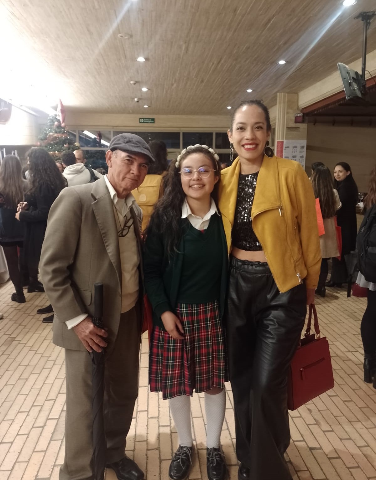 Foto de una estudiante junto a una maestra y un maestro