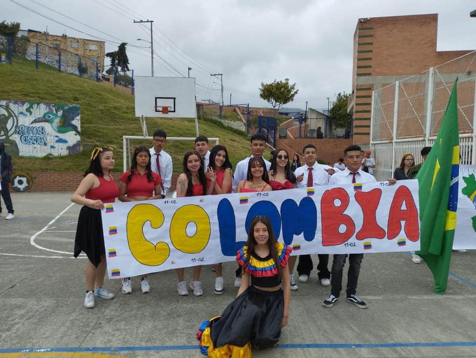 Estudiantes en el patio del colegio mostrando una pancarta que dice Colombia