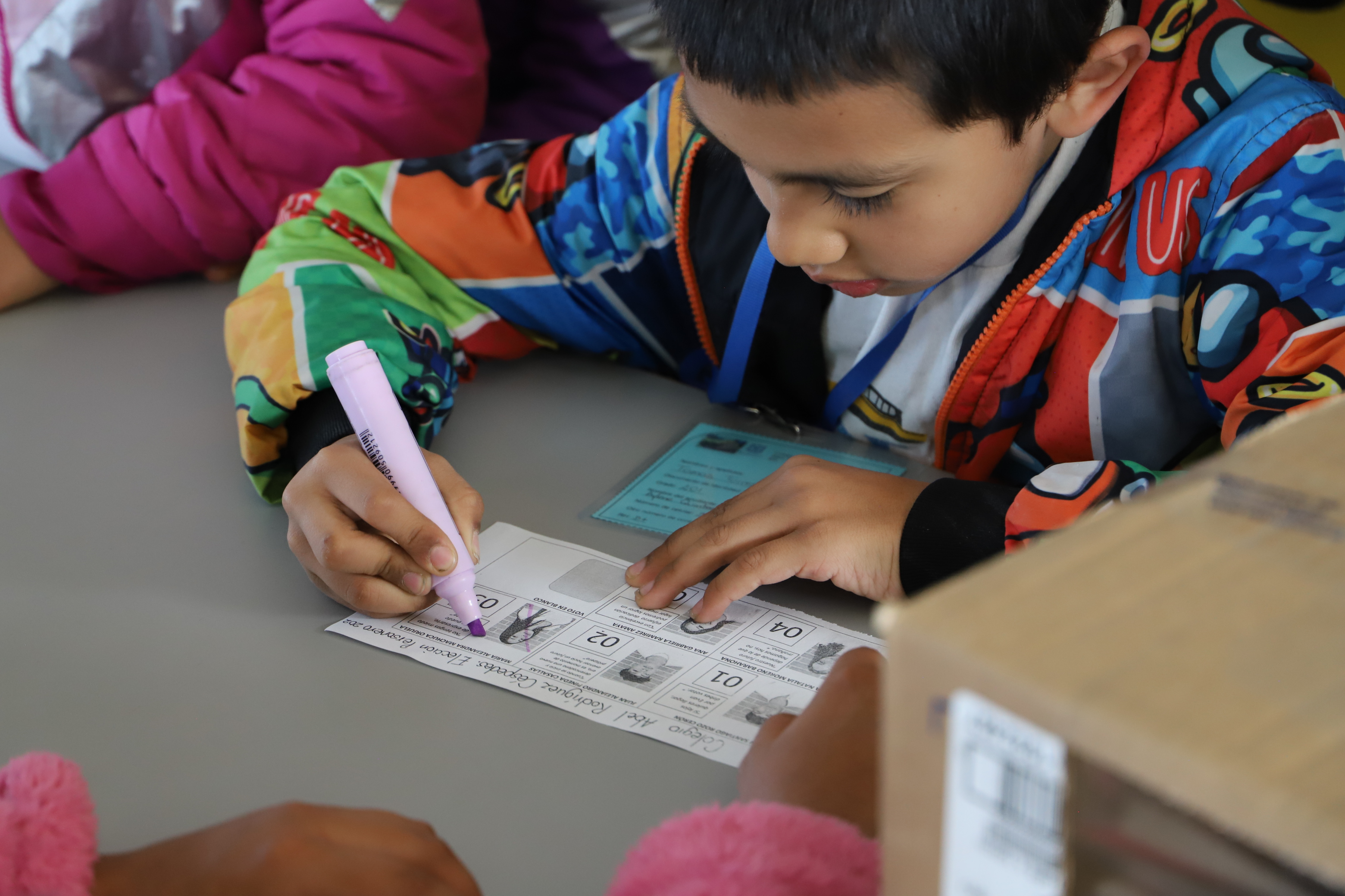 Niño marcando en un tarjetón de votación