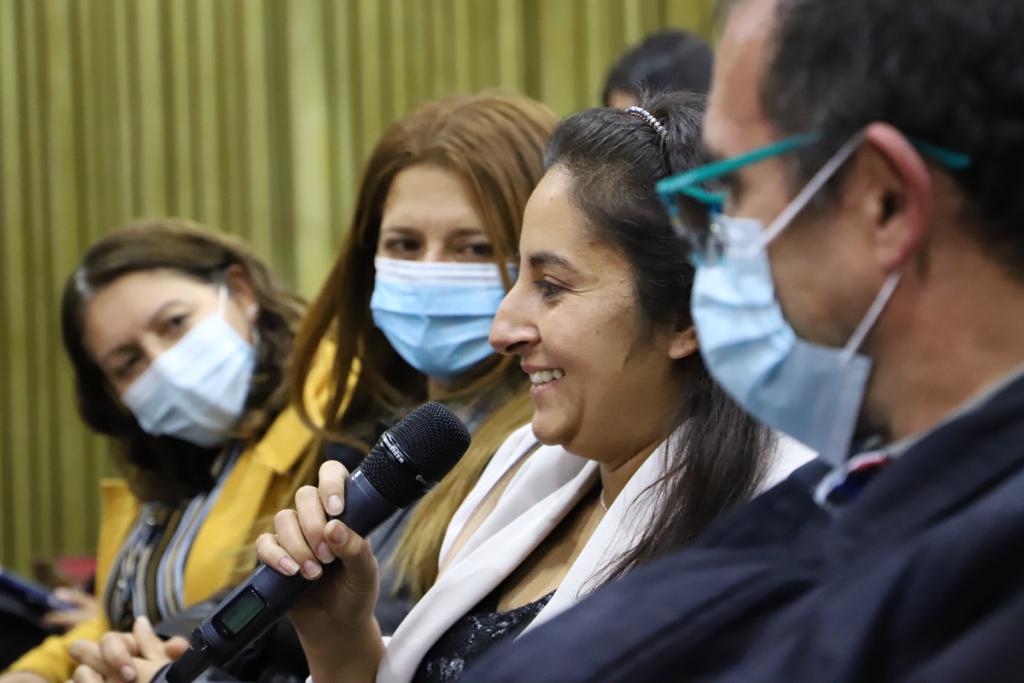 Fotografía de una maestra hablando por micrófono