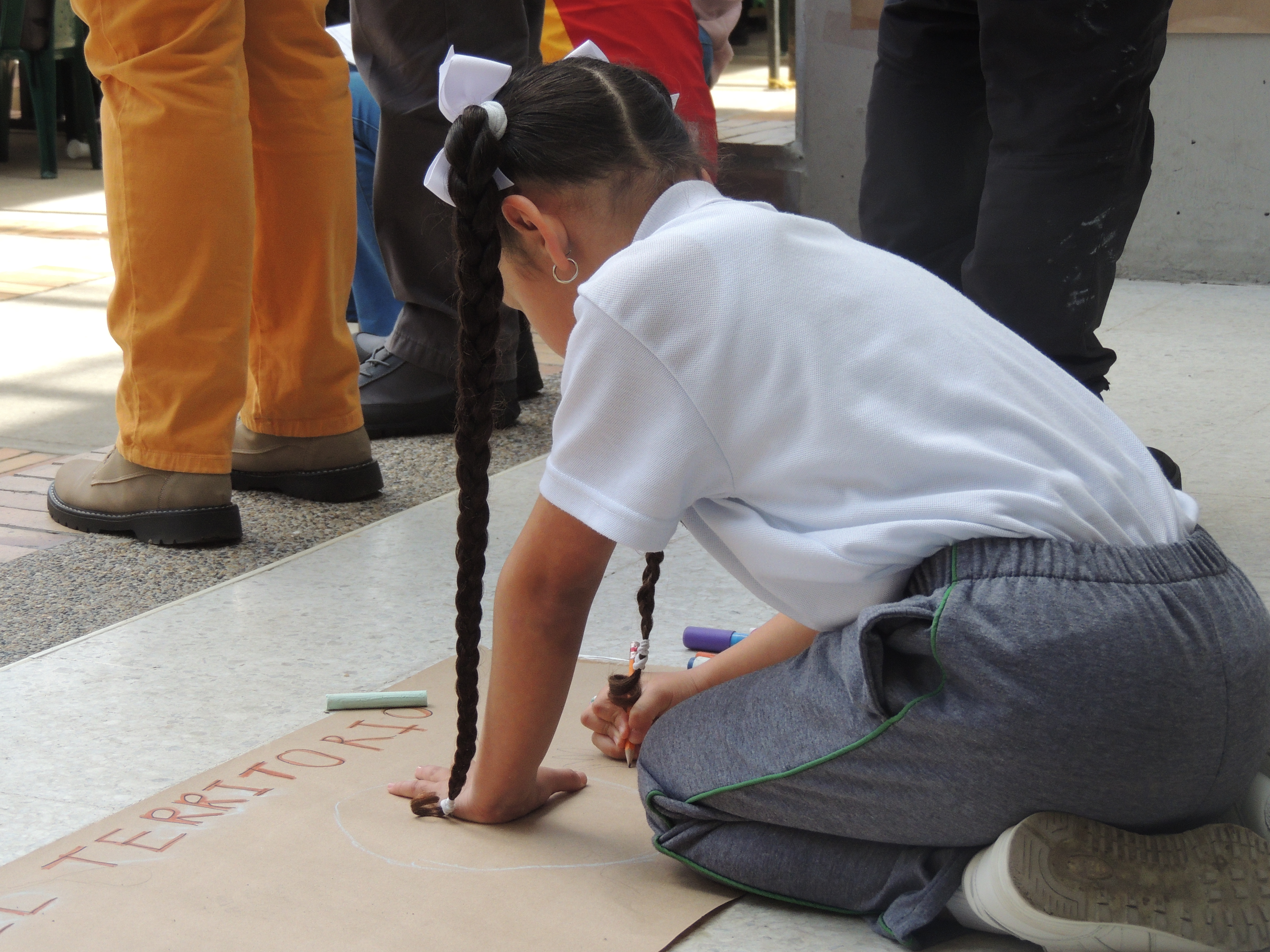 Foto de una niña haciendo un dibujo en el suelo