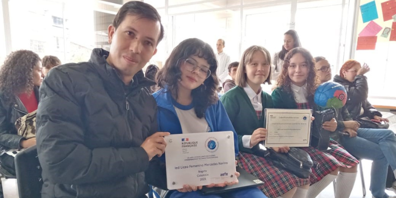 Foto de un maestro sentado junto a tres estudiantes