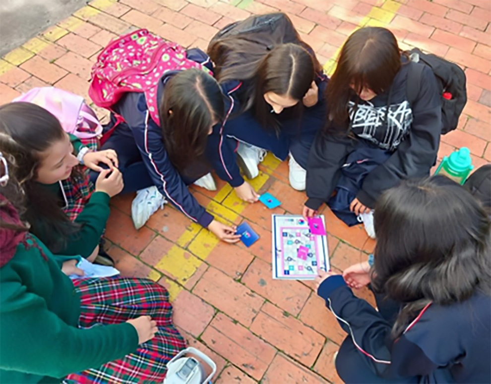 Niñas sentadas en el suelo, en circulo mirando un juego didáctico