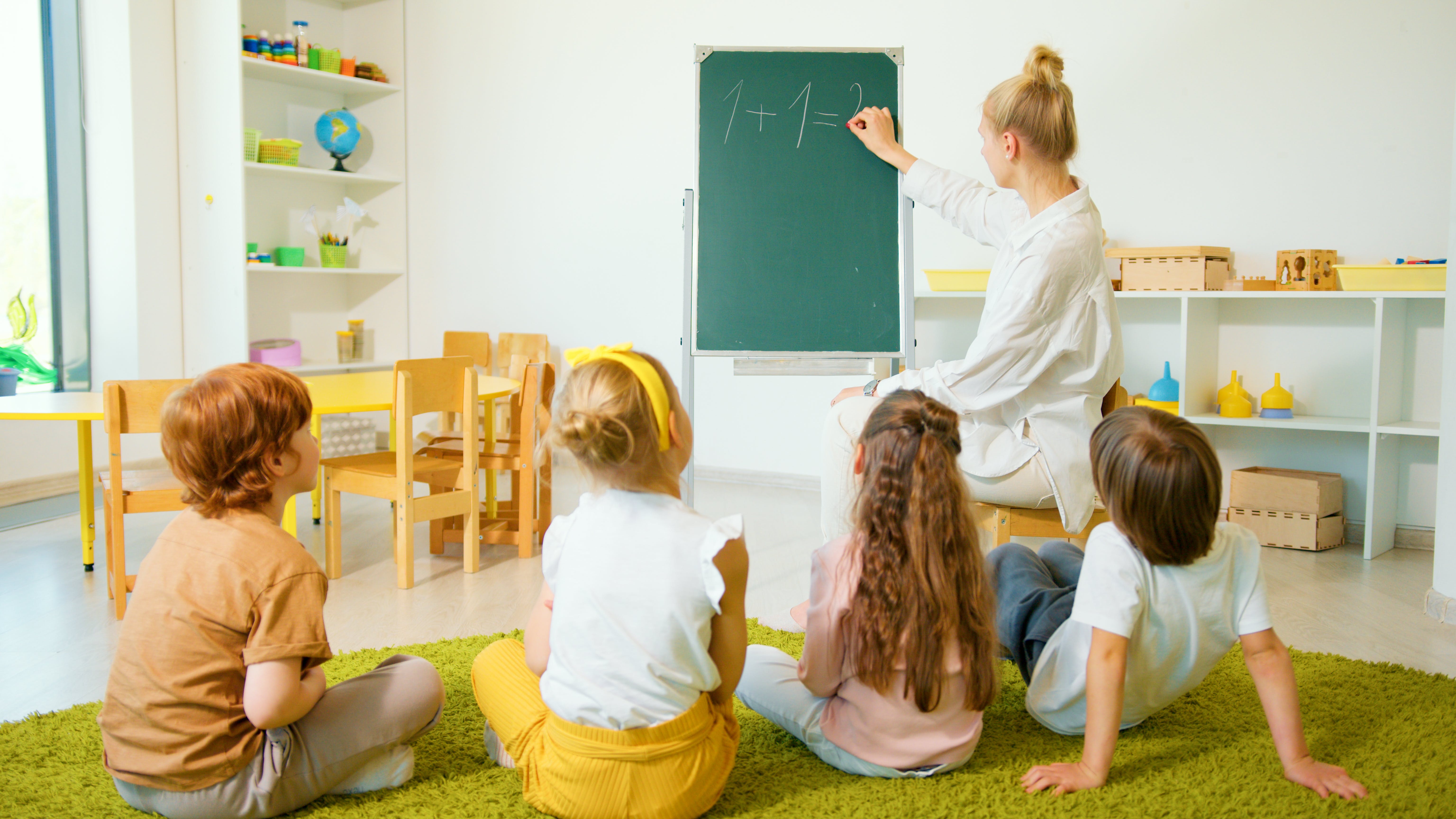 Una Mestra enseñando matemáticas a niños  y niñas pequeñas