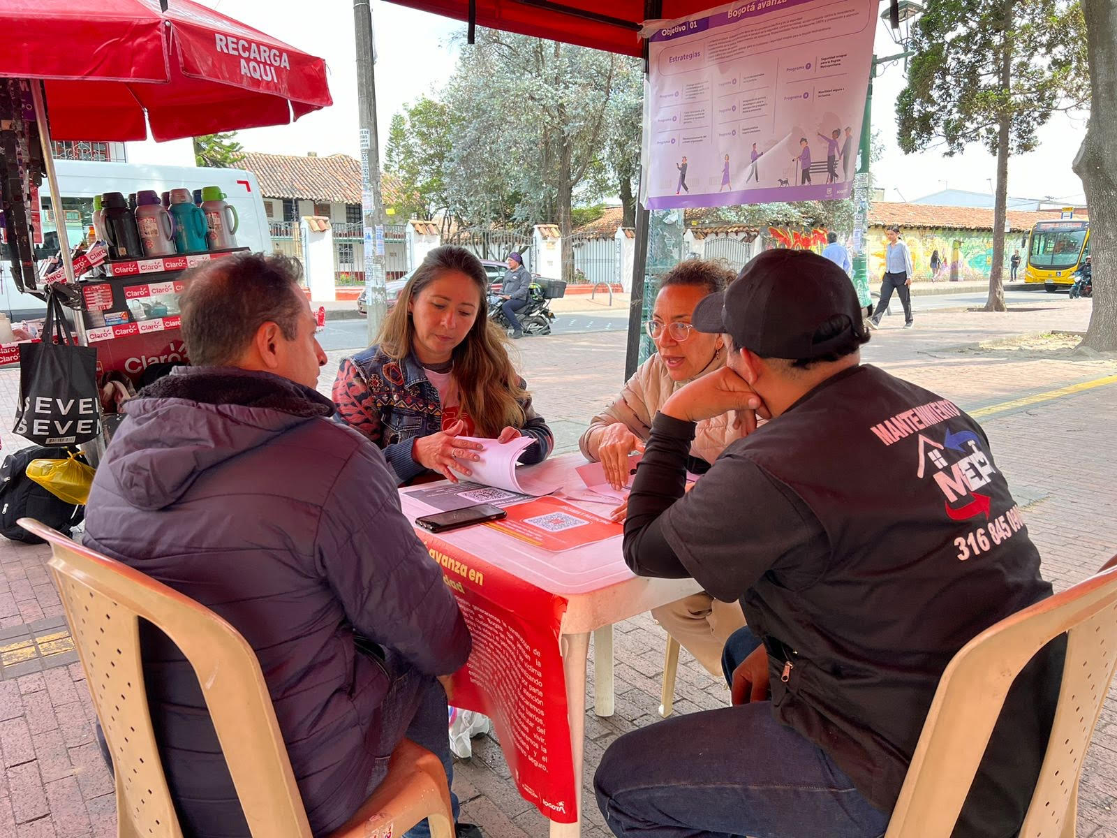 Dos mujeres y dos hombres hablando en en una mesa destinada a la participación ciudadana